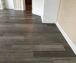 Designbelag Amtico mit Holzoptik in Wohnzimmer verlegt. Als Abschluss zur Wand eine weiße Sockelleiste von Döllken.