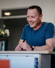 Ein Man lehnt sich auf einen Tresen und lächelt.