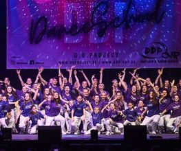 D.D.Project - Hip-Hop Tanzschule Dresden Energiegeladene Tanzgruppe in violetten Outfits bei einer Bühnenperformance, ideal für Hip-Hop, Showdance und Bühnenkunst.