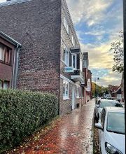 Der Fußweg vor dem Gebäude an einer Hecke