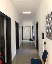 Flurbereich mit Türen auf der linken und rechten Seite, Flyer Aufhänger und einem Stuhl an der rechten Wand