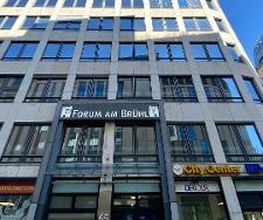 Außenansicht des Einganges zum WBS TRAINING Gebäude. Auf der Fassade sind mehrere Banner und Schilder von bekannten Unternehmen angebracht.