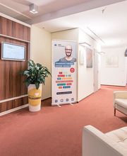 Heller und moderner Flur mit gemütlicher Sitzecke. Einige Zimmerpflanzen und Plakataufsteller sowie ein Aufsteller mit Informationsmaterial.