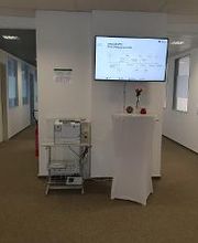 Flurbereich mit Fernseher und Stehtisch und links davon ein Teilnehmerdrucker