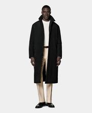 This knee-length black overcoat has a natural shoulder, padded interior, and hidden button closure. It features seam pockets with zips, inside pockets, and a single vent. Lined for added comfort and warmth.
