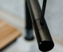 Die Nahaufnahme zeigt eine hochwertige, mattschwarze Design-Küchenarmatur von Quooker mit minimalistischer Formensprache. Der Fokus liegt auf der eleganten Linienführung und der präzisen Verarbeitung der Armatur, während der Hintergrund durch eine geringe Tiefenschärfe dezent verschwimmt. Die moderne Armatur fügt sich harmonisch in das exklusive Küchendesign ein und unterstreicht den zeitlosen Charakter hochwertiger LEICHT Küchen.