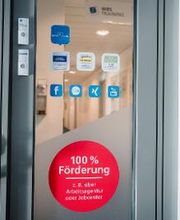 Tür mit einem runden Aufkleber mit der Aufschrift "100 % Förderung"