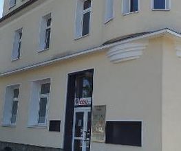Außenansicht des Gebäudes mit gelber Fassade.