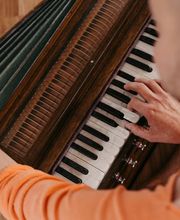 Detailaufnahme eines gespielten Harmoniums mit Fokus auf Hände und Instrument. Ideal, um die meditative und musikalische Begleitung von Yogastunden zu zeigen.