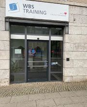Eingangstür des Gebäudes der Niederlassung WBS Training Heilbronn. Über der Tür hängt ein Schild mit der Aufschrift „WBS TRAINING – Unser Herz schlägt für Bildung“.