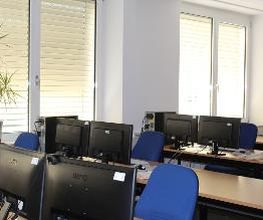 Schulungsraum mit mehreren Arbeitsplätzen mit jeweils 2 Bildschirmen, einem Bürostuhl und Tastatur und Maus.