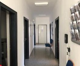 Flurbereich mit Türen auf der linken und rechten Seite, Flyer Aufhänger und einem Stuhl an der rechten Wand