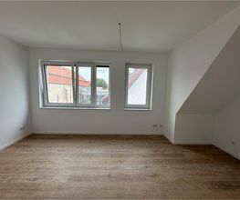 Heller Raum im Dachgeschoss mit Vinylboden und Dachschräge, fertig zum Einzug. Ein Projekt von AS-Bau.