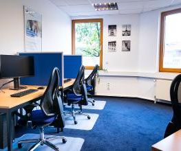 Ein Schulungsraum mit mehreren Arbeitsplätzen mit jeweils 2 Bildschirmen, einem Bürostuhl, Tastatur und Maus.