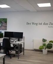 Ein Schulungsraum mit PC-Arbeitsplätzen. An der Wand befindet sich ein Bild und ein Wandtattoo mit der Aufschrift "Der Weg ist das Ziel. -Konfuzius" 