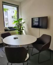 Tisch mit drei Stühlen sowie TV im Beratungsraum.