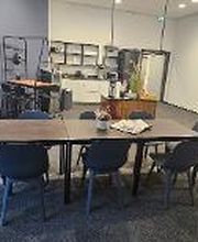 Gemütlicher Aufenthaltsraum mit Tischen und Stühlen. Im Hintergrund eine Küche.