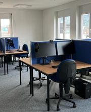 PC-Arbeitsplätze mit mehreren Monitoren, Tastatur, Maus und Headset.
