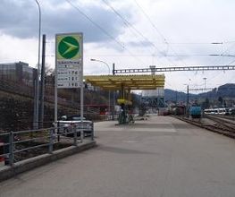 AGROLA Tankstelle in Herisau. Rechts Bahngleise gelegen. Tankstelle mit gelbem Gerüst. Im Vordergrund Totem mit AGROLA Diskus und Preisanzeigeschildern