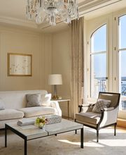 Elegant living room with neutral tones, large windows, and lake views at The Woodward Geneva suite.