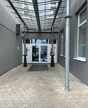 Außenansicht vom Eingangsbereich mit Glasüberdachung und weißer Türe.