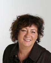 Eine Frau mit dunklen Haaren und dunkler Bluse.