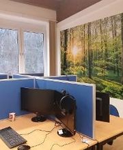 Mehrere abgetrennte PC-Arbeitsplätze mit Monitor, Tastatur, Maus und Headset.