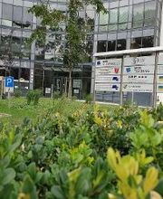 Außenansicht des Eingangbereiches mit Fensterfront und Schildertafel der ansässigen Unternehmen.