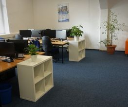 Schulungsraum mit mehreren PC-Arbeitsplätzen und einer orangenen Couch.