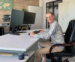 ein Teilnehmer am PC-Arbeitsplatz im freundlich gestalteten Schulungsraum mit heller Möblierung.