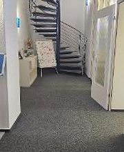 Flur der zu einer Wendeltreppe führt. Daneben ein Regal, rechts eine Tür.