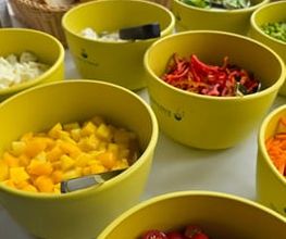 dean&david Catering | Karlsruhe - Buffetstation mit geschnittenen Tomaten, Mango, Paprika, Karotten, Gurken und Brot für individuelle Salate und frische Eventverpflegung.