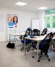 Heller Kursraum mit Tisch und Bürostühlen, Whiteboard und Arbeitsmaterialien.