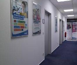 Flur zu mehreren Räumen. An der Wand mehrere WBS TRAINING Plakate.