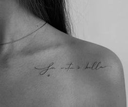Fineline Schriftzug-Tattoo "La vita è bella" auf der Schulter mit eleganten Linien in filigraner Handschrift.