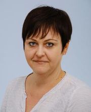 Frau mit kurzem Haar und großen blauen Augen schaut freundlich.