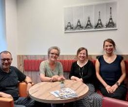Gruppenbild von dem Team der Region Leipzig. Die Personen sitzen in einer gemütlichen Sitzecke und lächeln fröhlich in die Kamera.