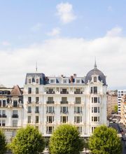 Exterior facade of The Woodward Geneva, a grand lakeside hotel with classic architecture and tree-lined streets.