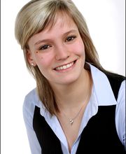 Portrait einer blonden Mitarbeiterin, die freundlich in die Kamera lächelt.