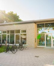 Außenansicht des Eingangsbereichs des Fröbel-Kindergartens Essener Straße mit Glasfront, Fahrrädern und begrüntem Vorplatz.
Fröbel-Kindergarten Essener Straße, Hamburg, © Fröbel, Foto: Martin Arnold. Alle Rechte vorbehalten.