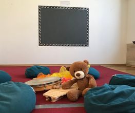 Gruppenraum mit Sitzkissen, Teddybär und Musikinstrumenten für kreative Kinderstunden - Luft(T)raum Leipzig