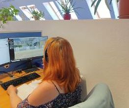 Teilnehmerin sitzt am Arbeitsplatz mit Headset und lernt virtuell