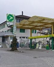 AGROLA Tankstelle in Kaltbrunn; geschwungen Überdachung. Zwei Tanksäulen. In Kurve gelegen. Rechts Erdsäcke.