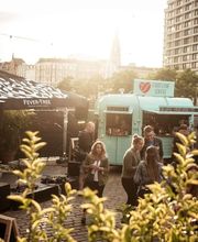 FirstLoveCoffee GmbH - Kaffee Catering Berlin - Mobiler Kaffeeanhänger bei Outdoor-Event in der Stadt mit Gästen, Musikbereich und Kaffeespezialitäten für Firmenfeier, Sommerfest oder Kundenveranstaltung.