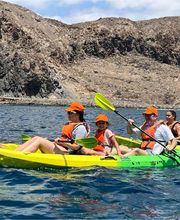 familia haciendo kayak en el mar con montaña de fondo
