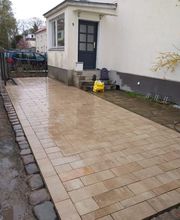 Neu angelegte Zufahrt und Eingangsfläche mit rechteckigen Pflastersteinen in natürlichen Beige und Sandtönen. Die Pflasterarbeiten von KK GaLaBau in Berlin Charlottenburg schaffen eine belastbare und gepflegte Fläche vor dem Wohnhaus.
