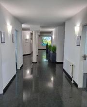 Moderner Flur mit weißen Wänden und grauem Fliesenboden