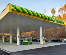 AGROLA Tankstelle in Illnau; an Dach Luftballone in gelb und grün angebracht; mehrere Tanksäulen; im HIntergrund TopShop; rechts Bäume