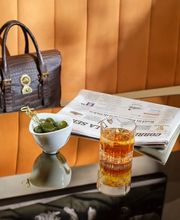 One of the tables in Il Salotto Lobby Lounge with a cocktail, green olives and a newspaper.