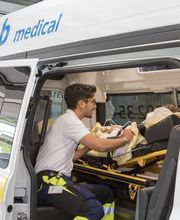 Mitarbeiter easyCab medical betreut Patienten, der auf Stryker liegt im Krankentransportfahrzeug